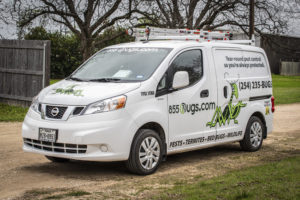 An 855Bugs pest control van is pictured on a dirt driveway.