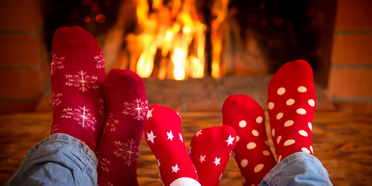 An image of three pairs of feet wearing red socks with white polkadots in-front of a fire in the fireplace. Winter pests bl o